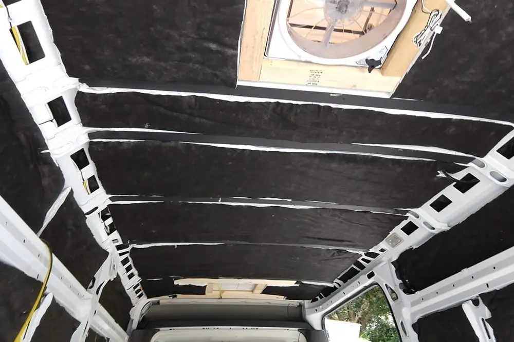 Wand van een bestelbus met isolatiemateriaal strak aangebracht tussen de carrosserieribben.