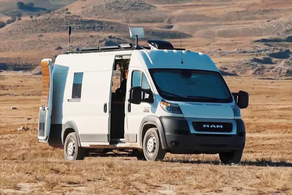 Een enkele camper op een leeg grindveld in de avondschemering.
