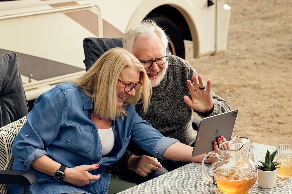 Laptop op een campertafel bij een open schuifdeur met uitzicht op een open landschap.
