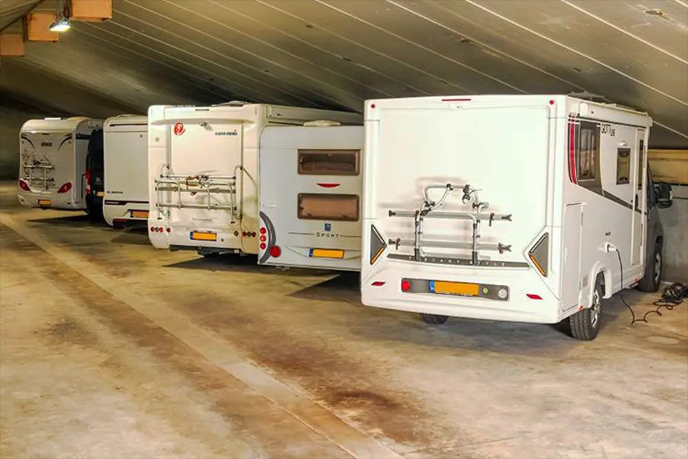Hand die de aftapkraan van de watertank onder een camper opendraait.