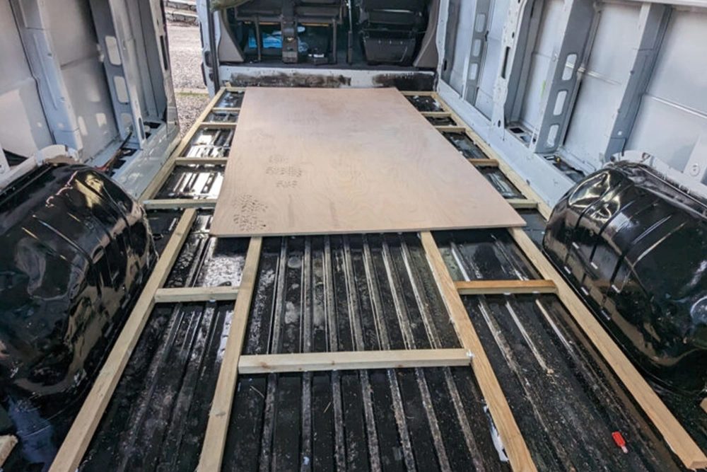 Handgetekende indelingsschets en gereedschap op een werkbank met een bus op de achtergrond.